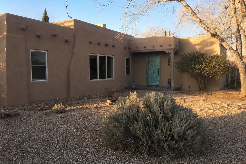 Adobe-style Santa Fe home with smooth earth-tone stucco and a turquoise door